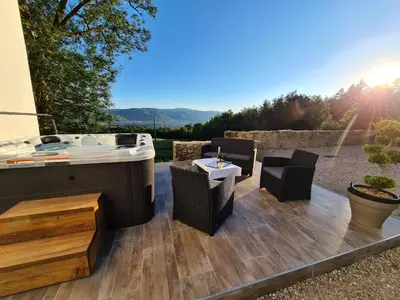 a hot tub on a patio with a table and chairs at Gîte confortable avec SPA privé et confort moderne in Pont-de-Larn