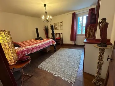 a bedroom with a bed and a chair and a window at L'Ancienne Forge in Villarzel-du-Razès