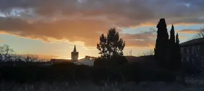 a sunset with a church and a clock tower at Le Coq du Nord - Mailhac Gîte et Chambres d'Hôtes in Mailhac