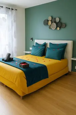 a bedroom with a large yellow bed with blue pillows at Le bourget - Suite romantique in Narbonne
