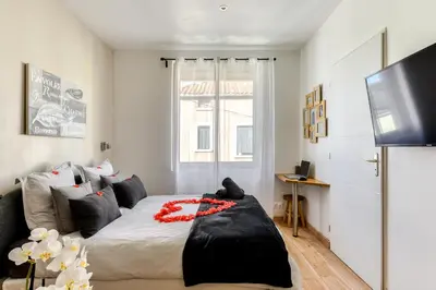 a bedroom with a bed and a flat screen tv at Le Bourget - Envolée Romantique in Narbonne