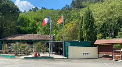 a man standing in front of a building with trees at Camping La Bernede in Rennes-les-Bains