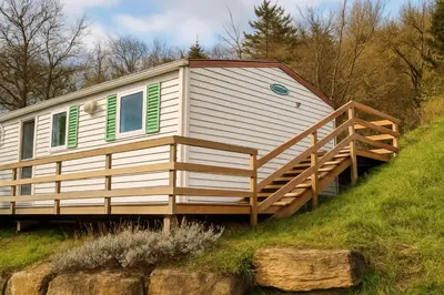 a tiny house with a deck on a hill at Camping La Bernede in Rennes-les-Bains