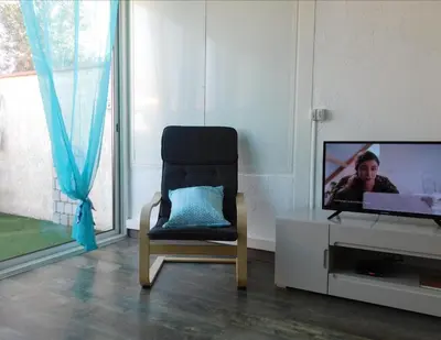a living room with a chair and a tv at LA MAISON DU LAC climatisée et WiFi gd F3 in Port-la-Nouvelle