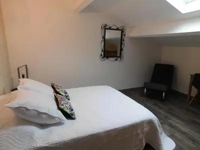 a bedroom with a bed with a mirror and a chair at LA MAISON DU LAC climatisée et WiFi gd F3 in Port-la-Nouvelle