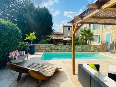 a swimming pool with a bench next to a house at Aux Berges du Libre in Félines-Termenès