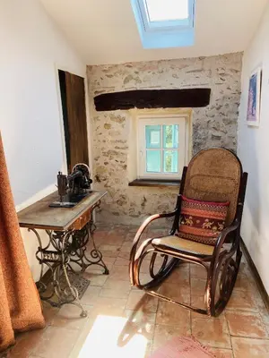 a chair in a room with a table and a window at Aux Berges du Libre in Félines-Termenès