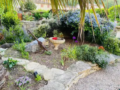 a garden with a large stone bowl and flowers at Aux Berges du Libre in Félines-Termenès