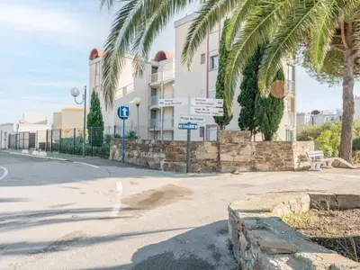 a building with palm trees and street signs in front of it at Apartment Les Portes de la Plage by Interhome in Gruissan