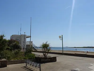 a park bench next to the beach with a street light at Apartment Les Portes de la Plage by Interhome in Gruissan