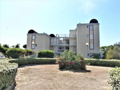a view of two buildings with bushes and flowers at Apartment Les Portes de la Plage by Interhome in Gruissan