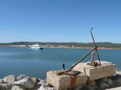 a boat in the water with a statue on the shore at Apartment Les Portes de la Plage by Interhome in Gruissan