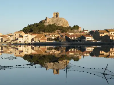a town with a castle on a hill next to a body of water at Apartment Les Portes de la Plage by Interhome in Gruissan
