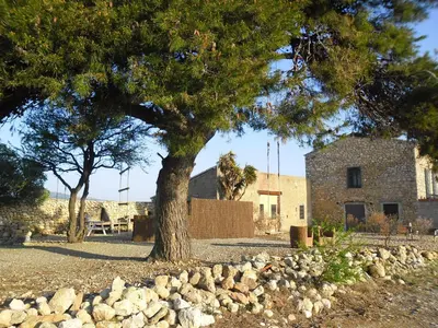 a tree and rocks in front of a building at Mas des 4 Vents in Fitou