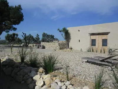 a white building with a wooden door in a yard at Mas des 4 Vents in Fitou
