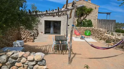 a swing in front of a building with a stone wall at Mas des 4 Vents in Fitou