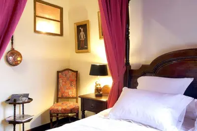 a bedroom with a bed with red curtains and a chair at MAISON DE NOSTRADAMUS*** OCCITANIE INSOLITE in Alet-les-Bains