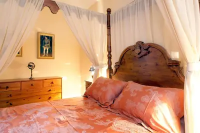 a bedroom with a large wooden bed with curtains at MAISON DE NOSTRADAMUS*** OCCITANIE INSOLITE in Alet-les-Bains
