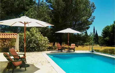 a pool with two chairs and two umbrellas next to it at Cozy Home In Pouzols-Minervois in Pouzols-Minervois