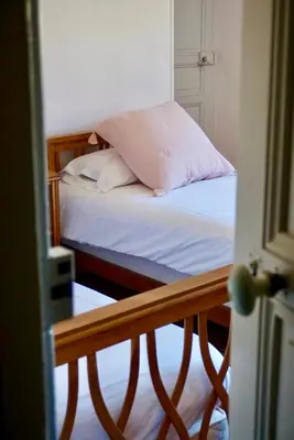 a small bed with white sheets and a pink pillow at La Bastide Saint Etienne in Cournanel