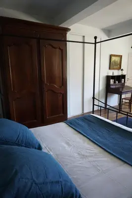 a bedroom with a bed with a wooden cabinet and a table at La Bastide Saint Etienne in Cournanel