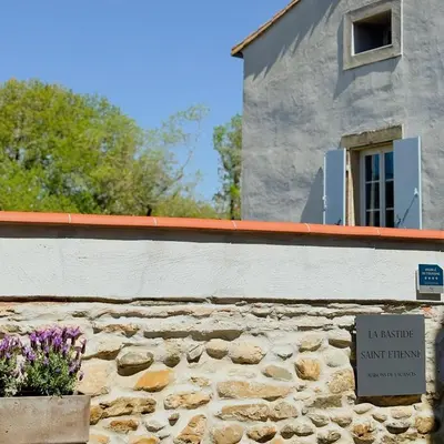 a building with a sign in front of a stone wall at La Bastide Saint Etienne in Cournanel