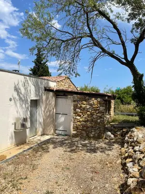 a stone building with a garage and a tree at Le Fenouillet Cottage proche des Grands Buffets in Narbonne