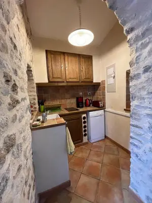 a kitchen with wooden cabinets and a stone wall at Le Fenouillet Cottage proche des Grands Buffets in Narbonne