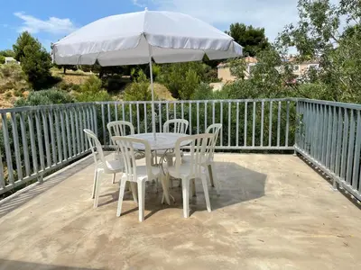 a table and chairs with an umbrella on a deck at Le Fenouillet Cottage proche des Grands Buffets in Narbonne