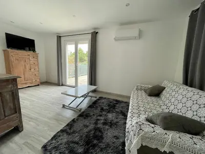 a living room with a couch and a sliding glass door at Le Fenouillet Cottage proche des Grands Buffets in Narbonne
