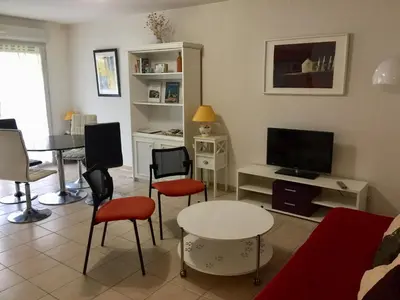 a living room with a table and chairs and a tv at Les Capucins in Carcassonne