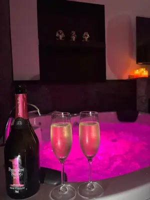 two wine glasses sitting on a table next to a bottle at Love Room L'instanté - Suite 