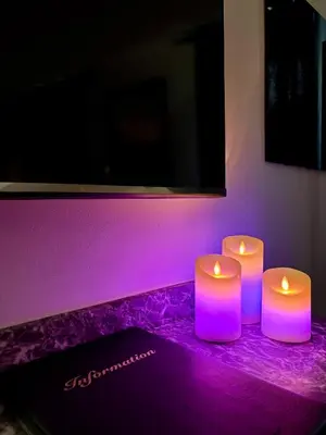three candles sitting on a table with purple lighting at Love Room L'instanté - Suite 