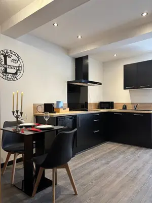 a kitchen with black cabinets and a table with chairs at Love Room L'instanté - Suite 