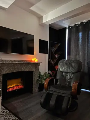a black leather chair in a living room with a fireplace at Love Room L'instanté - Suite 