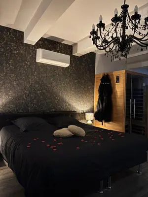 a bedroom with a black bed and a chandelier at Love Room L'instanté - Suite 