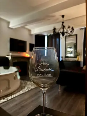 a wine glass sitting on a table in a living room at Love Room L'instanté - Suite 