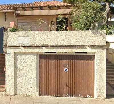 a garage with a brown door in front of a house at Maison 3 pièces 5-7pers Vue sur port, garage, clim in Gruissan