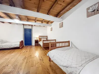 a bedroom with two beds and a wooden floor at Jardin Verdoyant à Soupex 