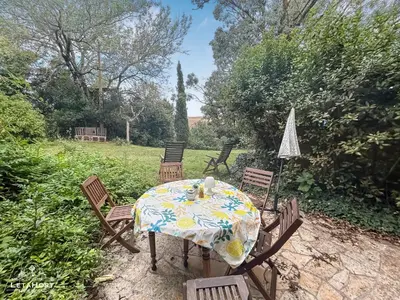 a table and chairs in a yard with a tablecloth on it at Jardin Verdoyant à Soupex 