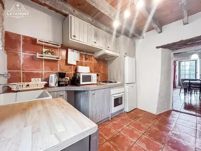 a kitchen with white cabinets and a counter top at Jardin Verdoyant à Soupex 