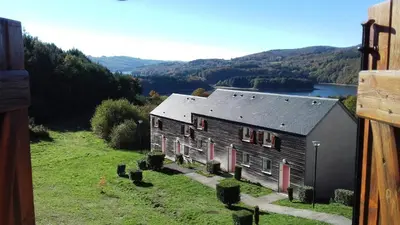 a house on a hill with a view of a lake at Gîte du Gua des Brasses au bord du lac de la Raviège in La Salvetat