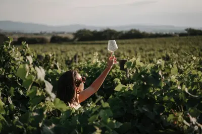 a woman in a field holding up a plastic bottle at Château Capitoul in Narbonne