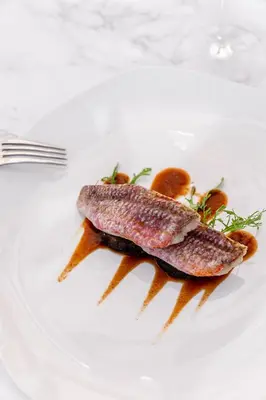 two pieces of fish on a white plate at Château Capitoul in Narbonne