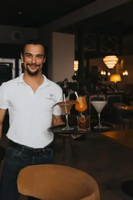 a man holding a tray with two drinks on it at Château Capitoul in Narbonne