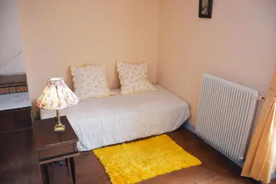 a bedroom with a bed with a lamp and a yellow rug at La Petite Maison in Cesseras