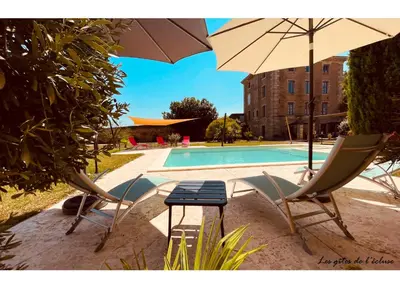 two chairs and an umbrella next to a swimming pool at Gites de l'écluse - La Côte de l'Or in Sallèles-dʼAude