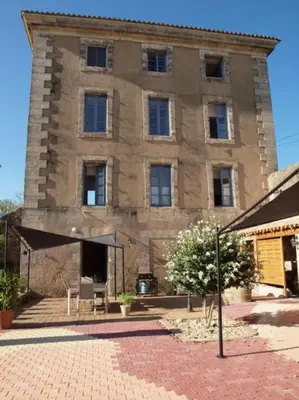 a large stone building with a patio in front of it at Gites de l'écluse - La Côte de l'Or in Sallèles-dʼAude