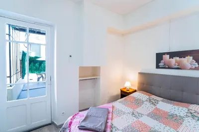 a bedroom with a bed and a window and a door at Appartement Les Halles , Climatisation, Terrasse, Garage in Narbonne
