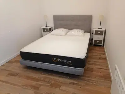 a bed in a bedroom with two night stands and two tables at T3 proche de la mer in Portel-des-Corbières